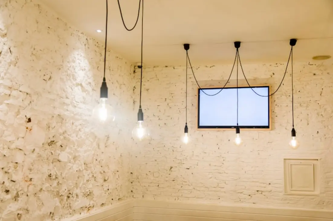 Hanging light bulbs with exposed wiring in a white brick room.