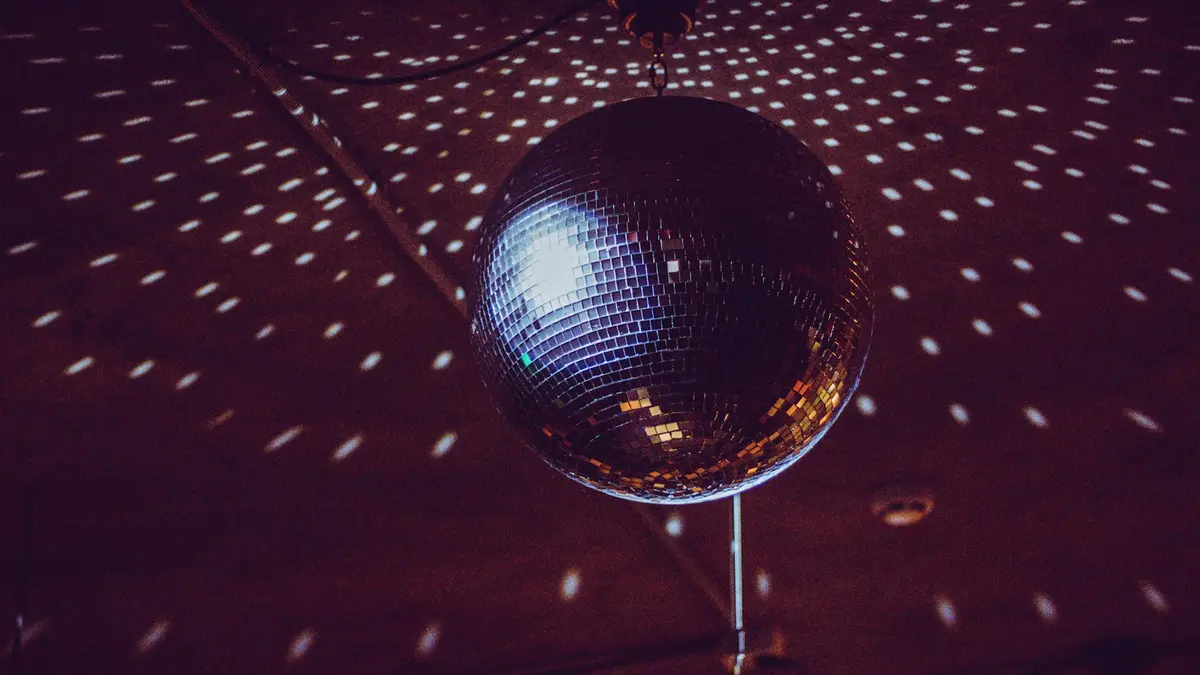A reflective disco ball hanging from the ceiling, casting light patterns on the surface below.