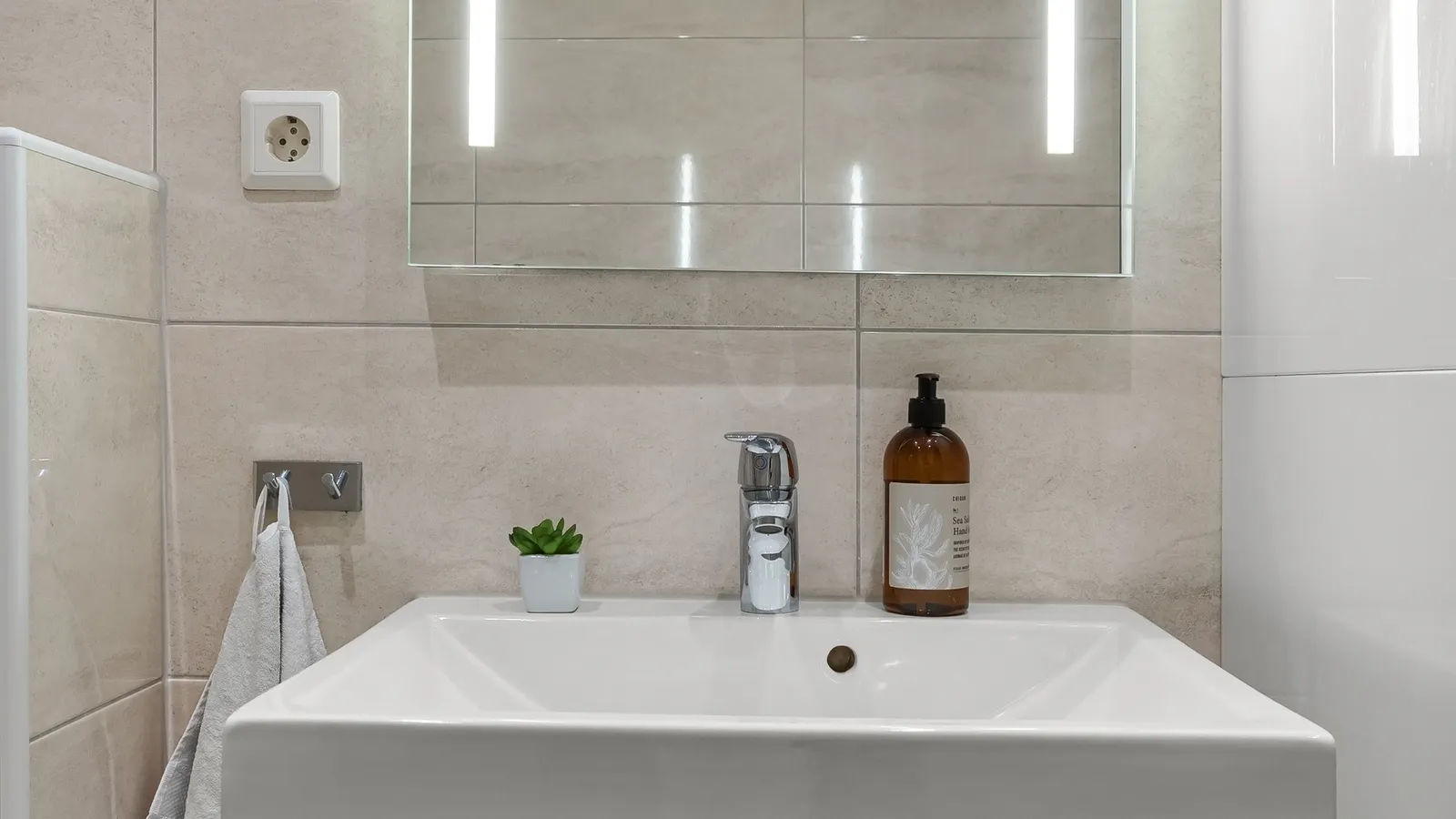 Modern bathroom with an illuminated mirror and layered vanity lighting.