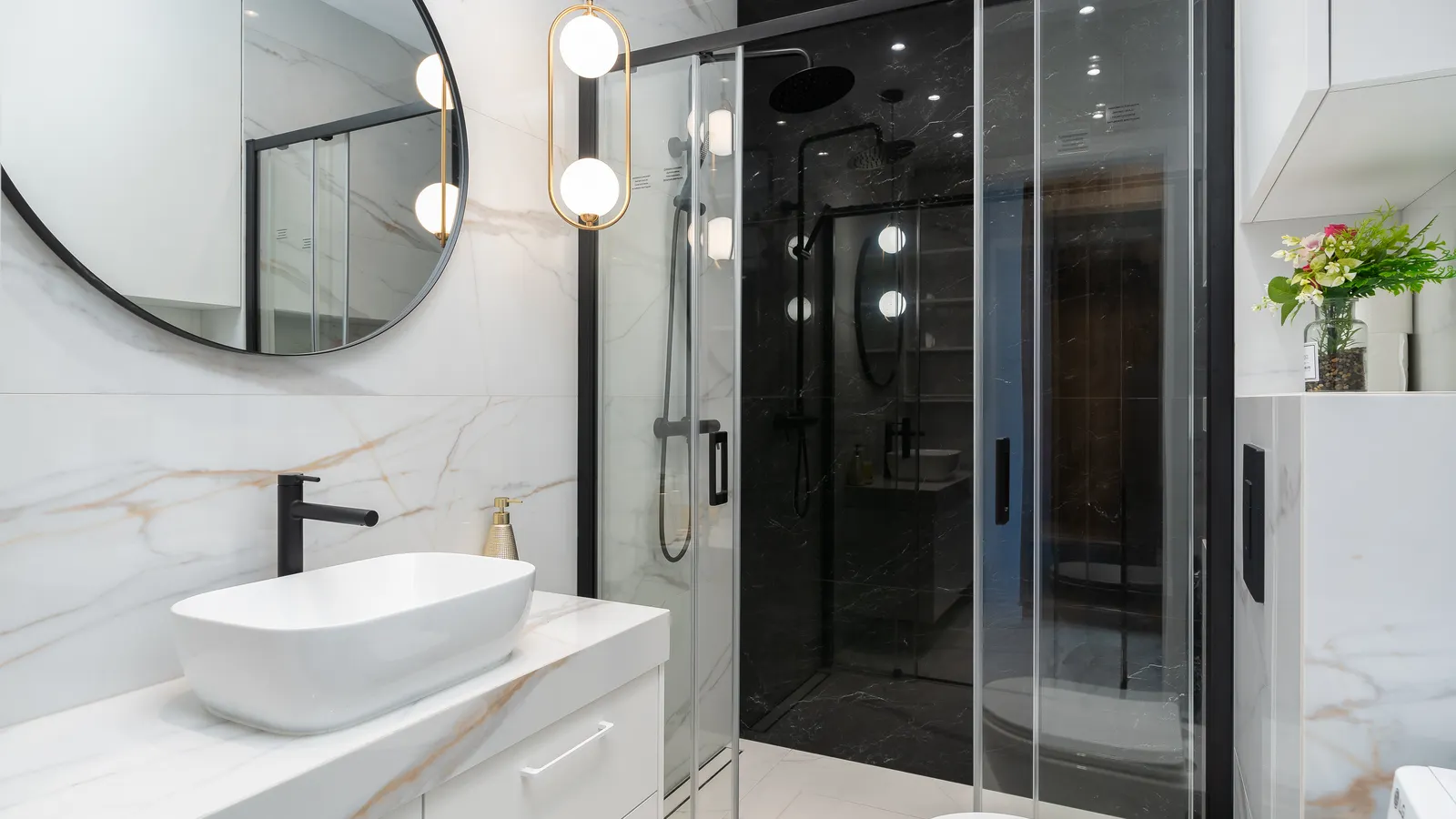 Modern bathroom with marble tile, contrasting grout, and warm vanity lighting.