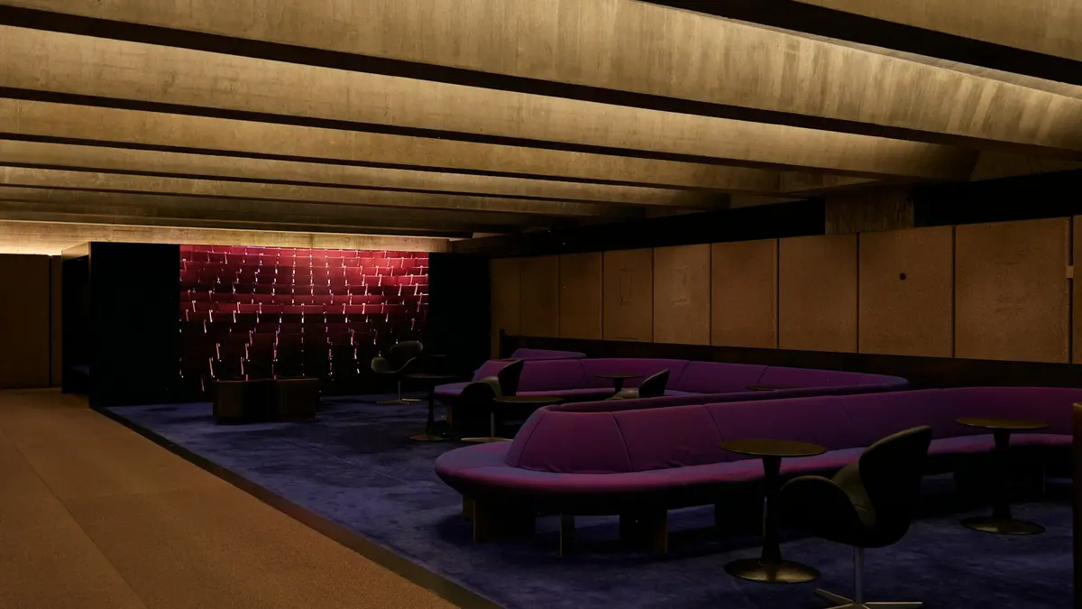 Modern lounge area featuring purple carpet and dim lighting contrasting with textured walls.