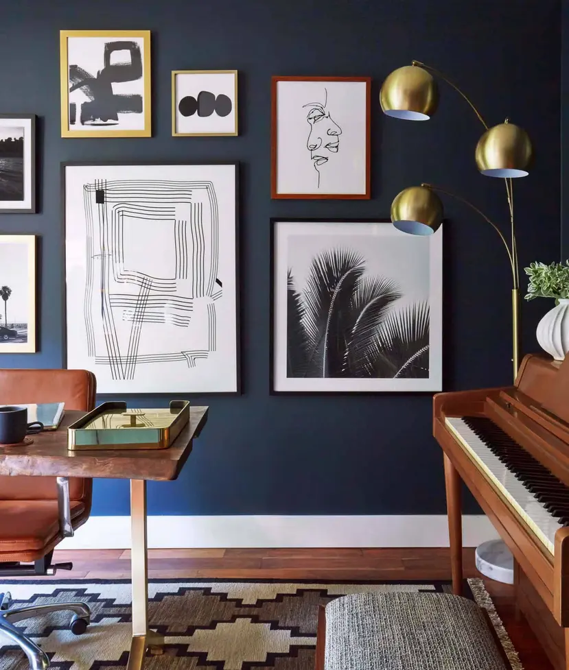 A modern living room featuring dark walls, framed art, a piano, and stylish floor lamps.