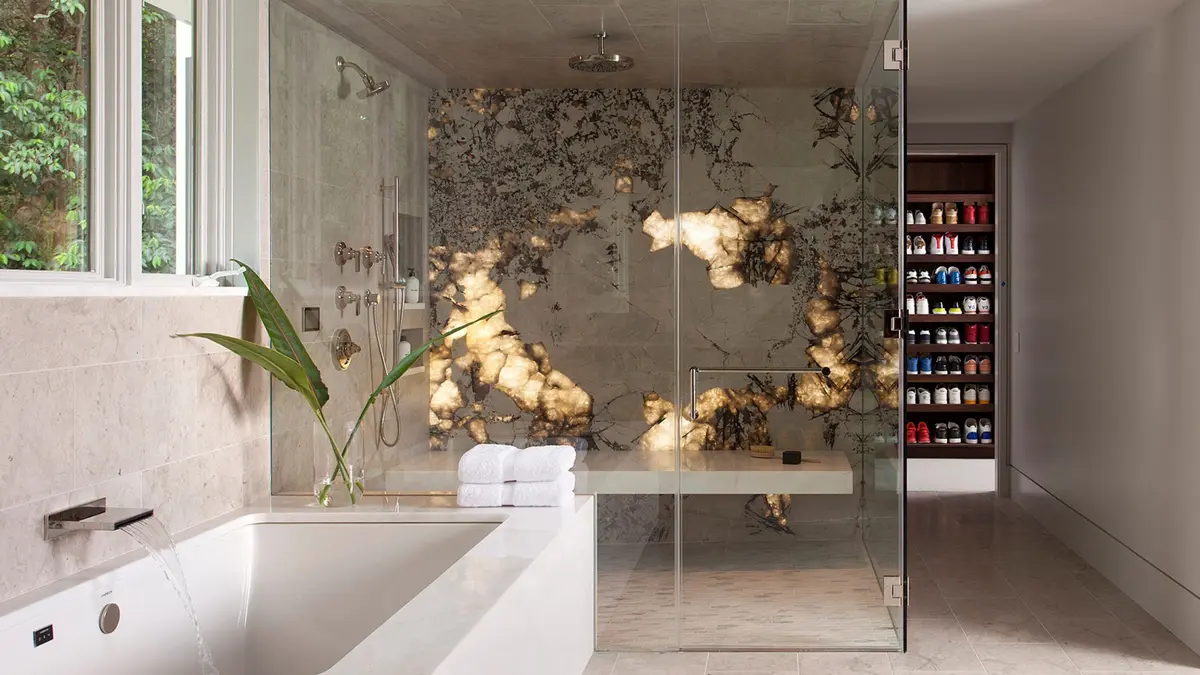 A modern bathroom featuring a glass shower, stone walls, and a freestanding bathtub.