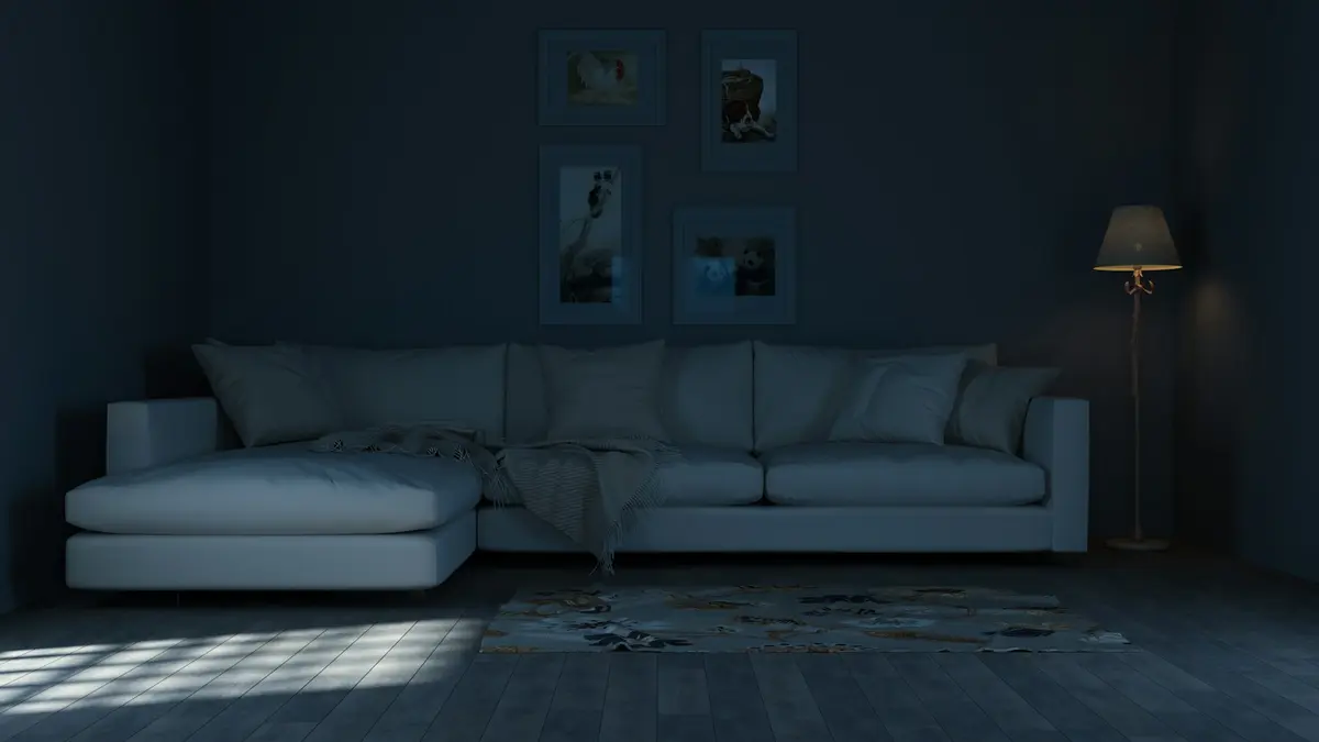 Cozy living room with a white sofa, warm lamp, and neutral wall colors in dim lighting.