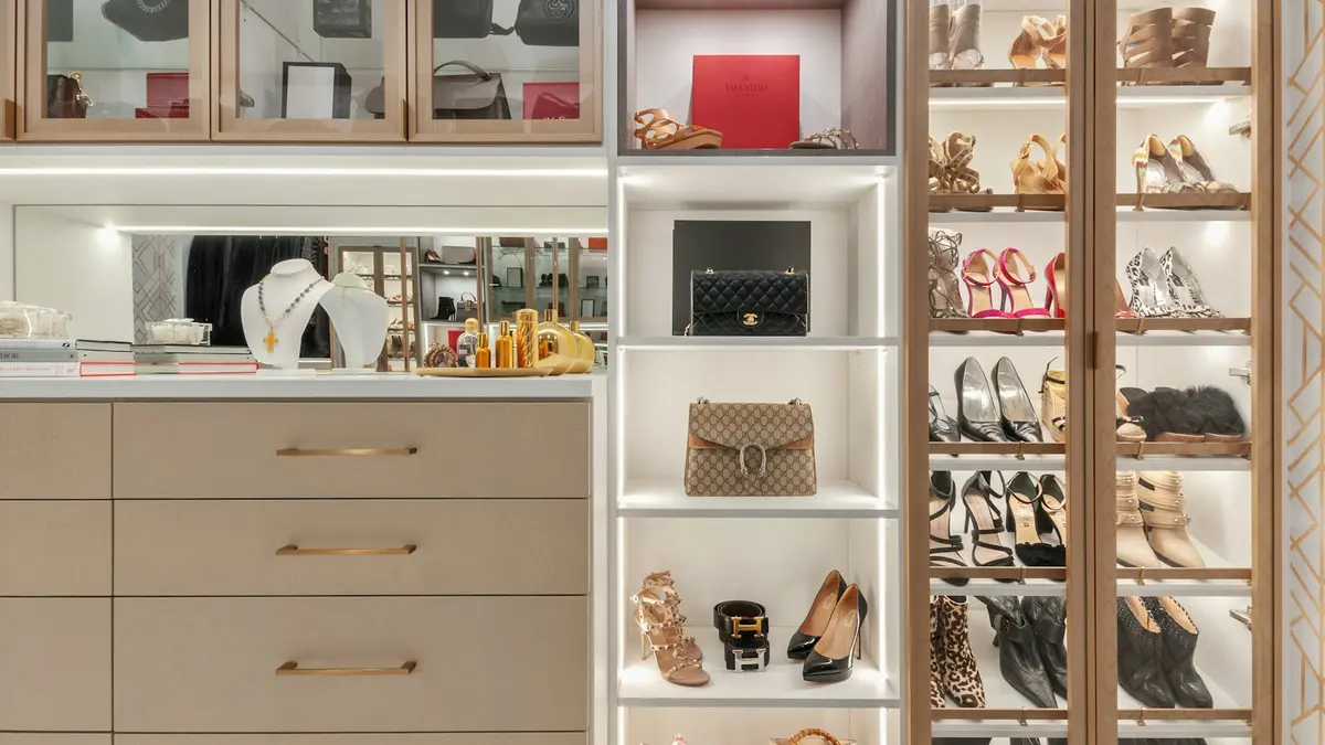 A stylish walk-in closet featuring organized storage, illuminated shelves, and a variety of shoes and accessories.