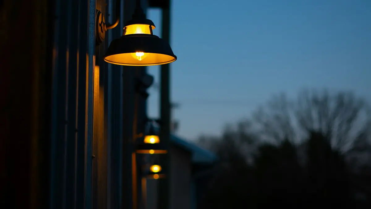 Exterior wall lights glowing softly against a twilight sky, illuminating a structured area.