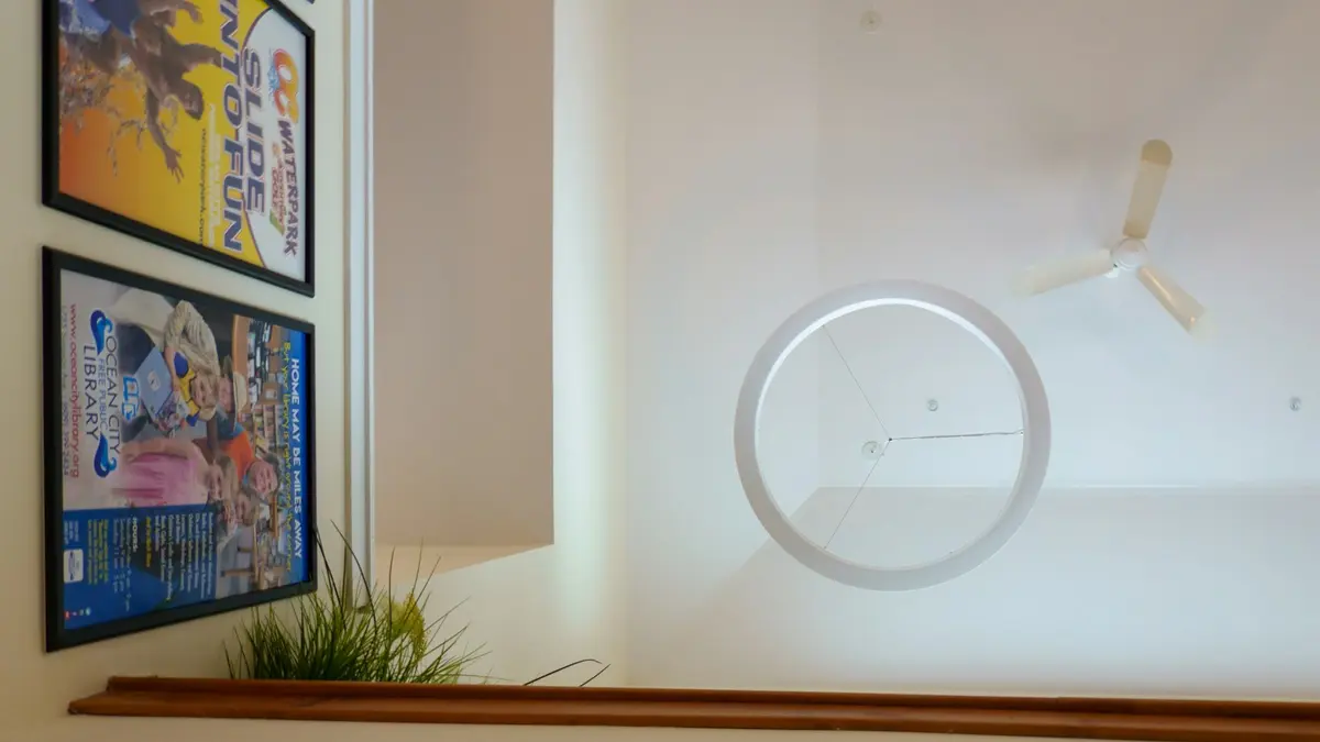 Ceiling with a fan and recessed lighting surrounded by framed posters.