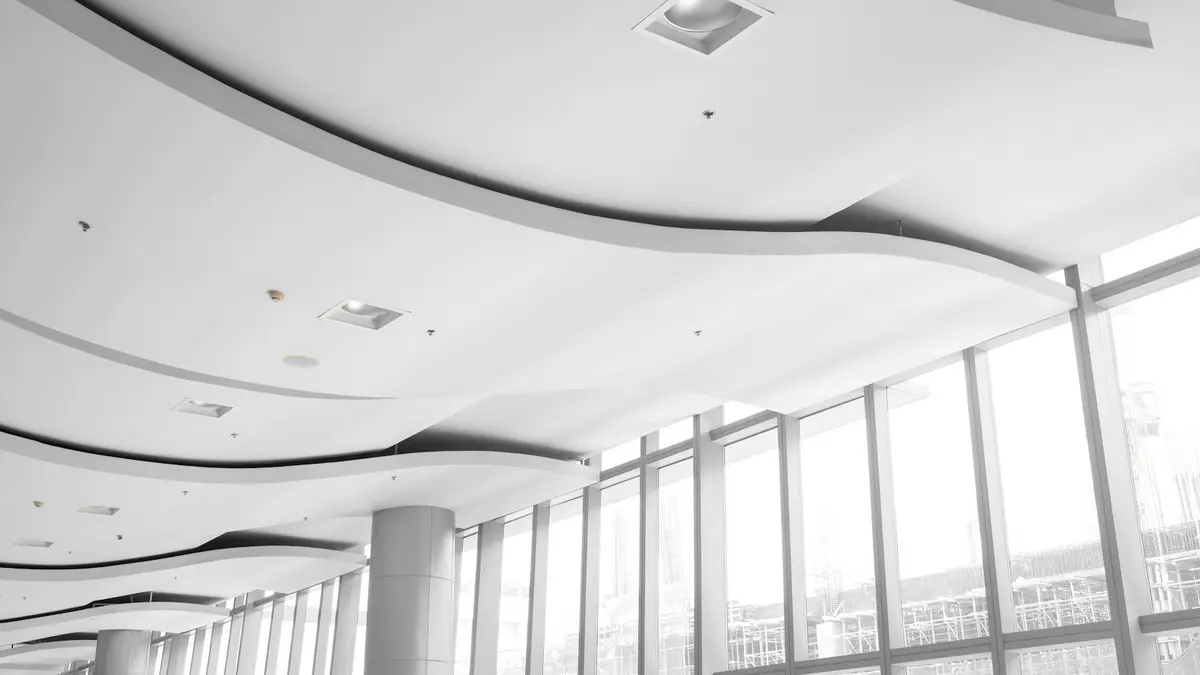 Curved ceiling with recessed lights casting soft shadows on a modern, spacious interior.